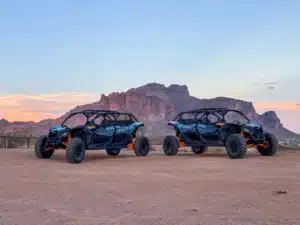 Two 2025 Can-Am Maverick X3 UTVs in front of the Superstition Mountains