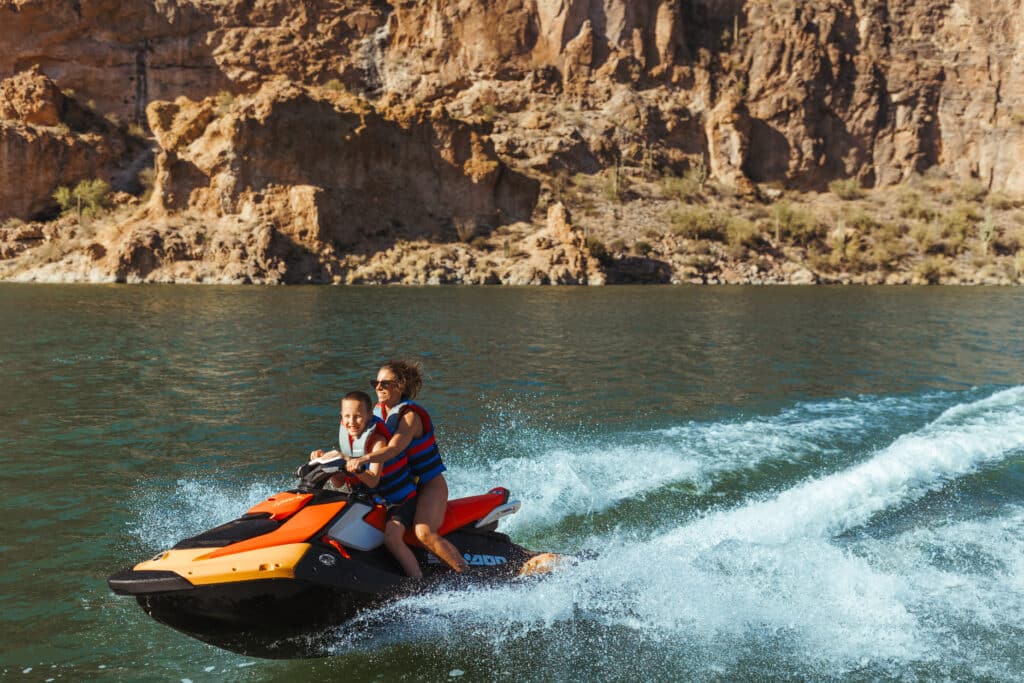 Mother And Child Riding A Sea-Doo Jet Ski Across Turquoise Canyon Lake Water In Arizona